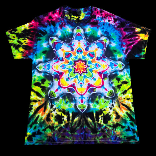 A short-sleeve crewneck t-shirt featuring a vibrant, multicolor psychedelic tie-dye pattern with a large symmetrical mandala design on the front, displayed flat against a solid black background.