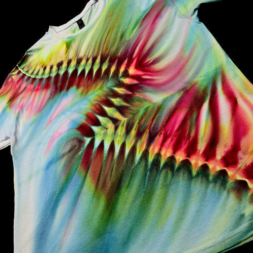 A close-up of a tie-dye t-shirt featuring a vibrant, swirling pattern of pink, green, yellow, and blue on a black background.