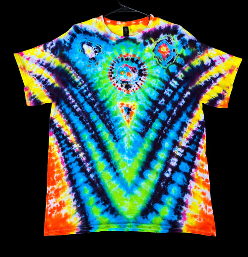 A vibrant tie-dye t-shirt with a symmetrical mandala design, featuring neon blue, green, yellow, orange, and purple patterns, hanging on a black hanger against a solid black background.