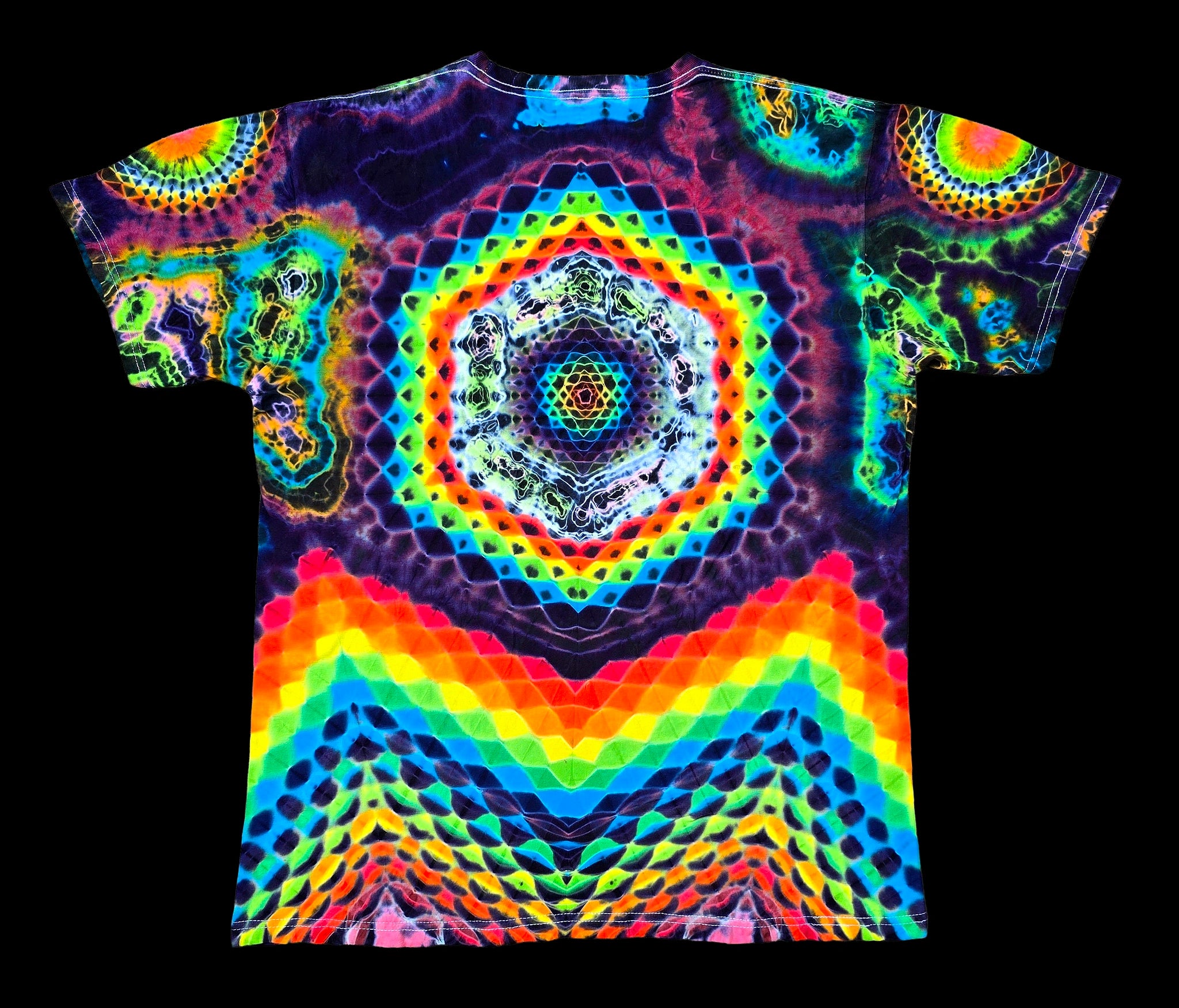 A short-sleeve t-shirt with a vibrant, symmetrical psychedelic tie-dye pattern featuring a central hexagonal mandala and rainbow wave motifs, displayed against a solid black background.