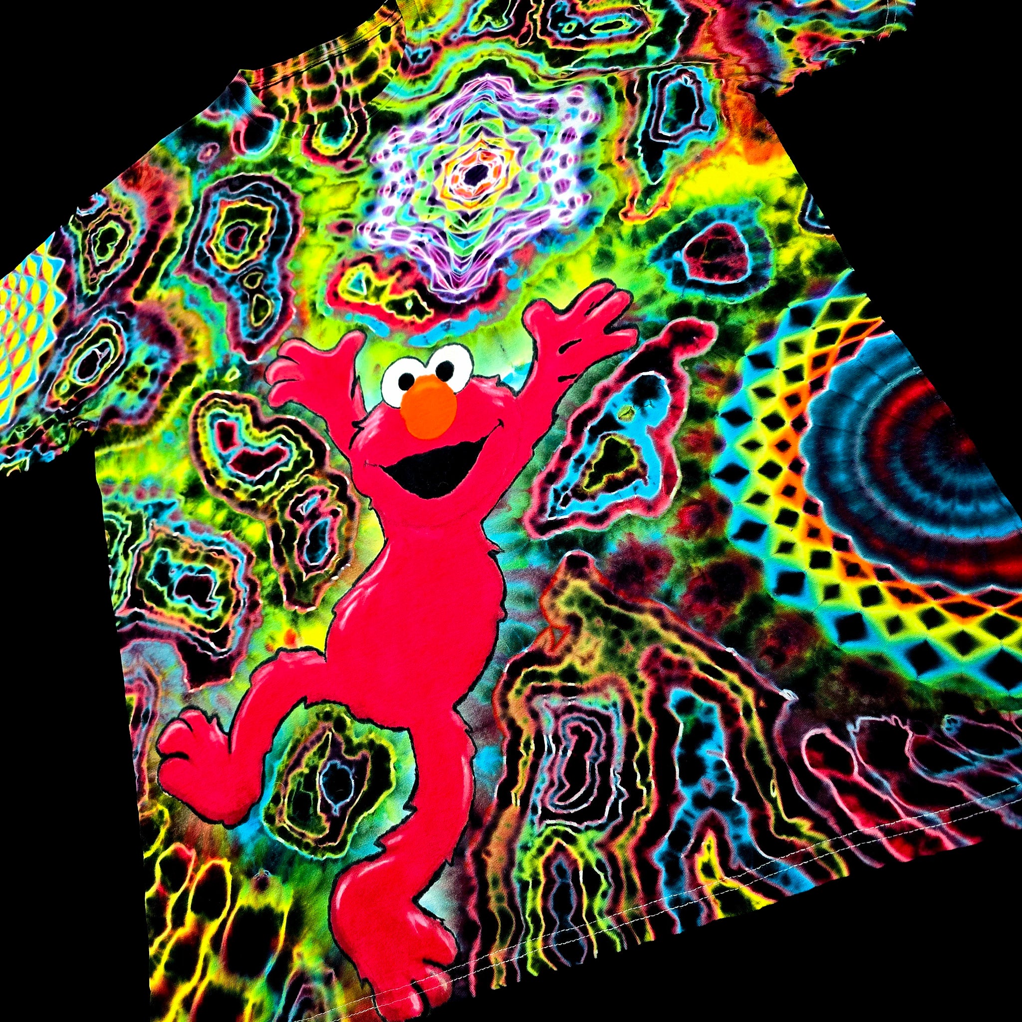 Front angled perspective view of tie dye shirt showing bright red Elmo graphic, geometric star, and side mandala pattern