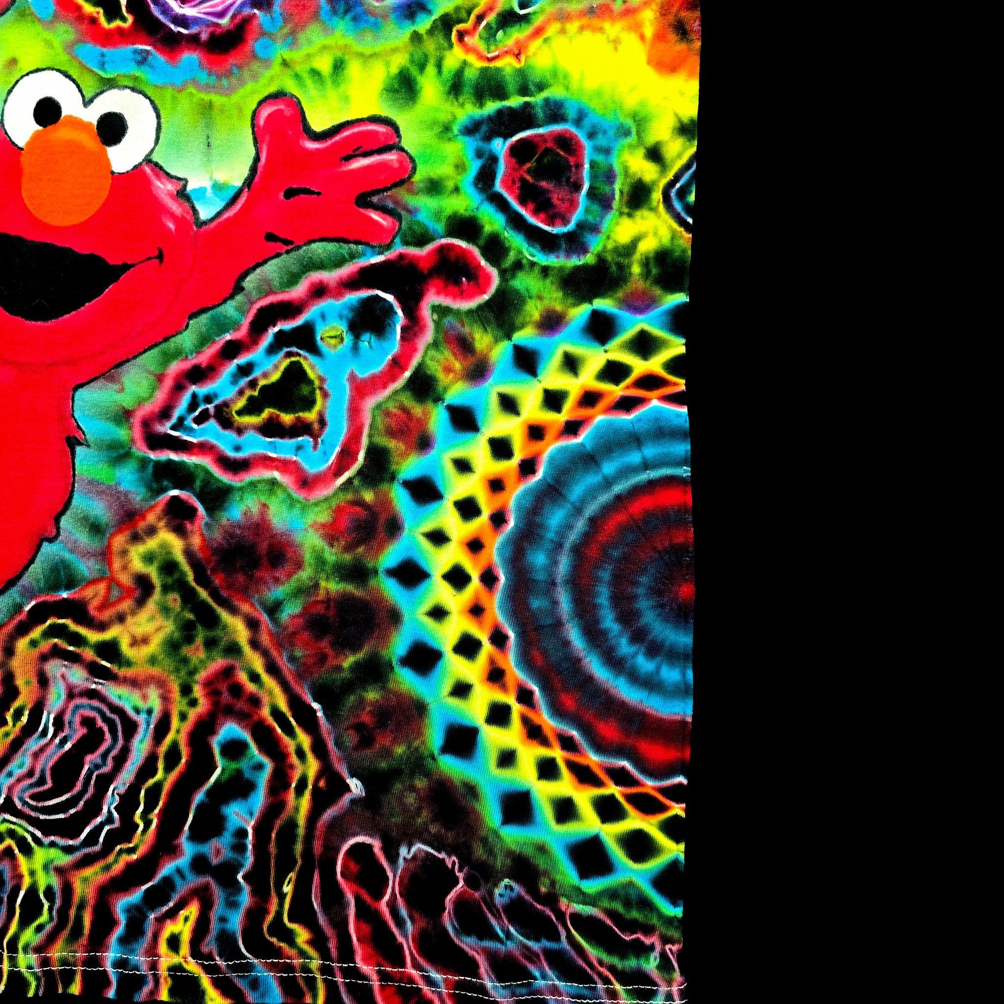 A highly vibrant, psychedelic tie-dye pattern featuring the character Elmo on the left, with swirling neon colors including green, yellow, blue, red, and pink, alongside a geometric mandala design on the right side.