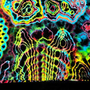 A close-up of a highly saturated tie-dye or psychedelic pattern with neon yellow, green, blue, pink, and purple outlines over a dark base. The fabric or material fills almost the entire frame, with a small black band visible along the bottom edge.
