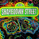 A psychedelic graphic with the text '420 SHAKEDOWN STREET' in white lettering on a bright green and yellow sign, set against a neon rainbow tie-dye background.