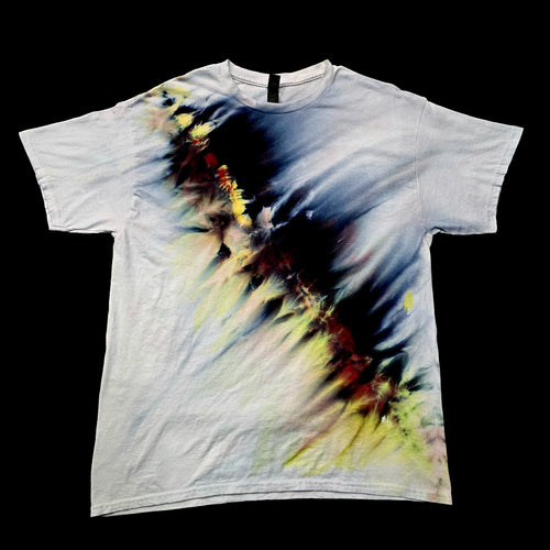 A white short-sleeve crewneck t-shirt featuring an abstract, painterly graphic print in black, blue, yellow, and red tones, laid flat against a solid black background.