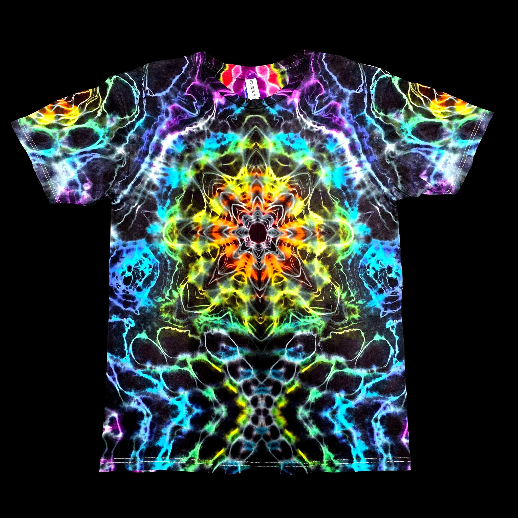 A short-sleeve crewneck t-shirt featuring a vibrant, symmetrical neon psychedelic print with a kaleidoscope of rainbow colors on a black base, shown flat against a solid black background.