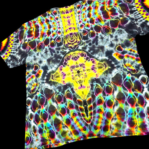 A short-sleeve t-shirt featuring a highly vibrant, psychedelic tie-dye pattern with neon yellow, pink, green, blue, and purple colors over a black and white base, shown against a solid black background.