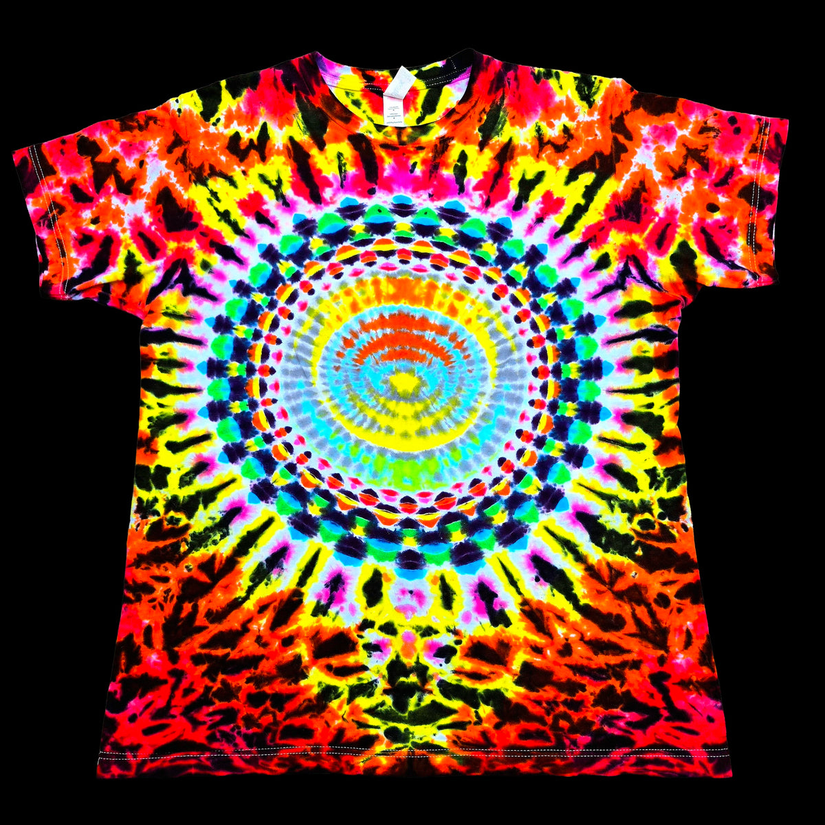 A short-sleeve crewneck t-shirt featuring a vibrant, psychedelic tie-dye pattern with a central mandala design. The shirt is covered in neon colors including pink, yellow, green, blue, orange, and purple in a symmetrical, radial burst pattern, presented flat against a solid black background.