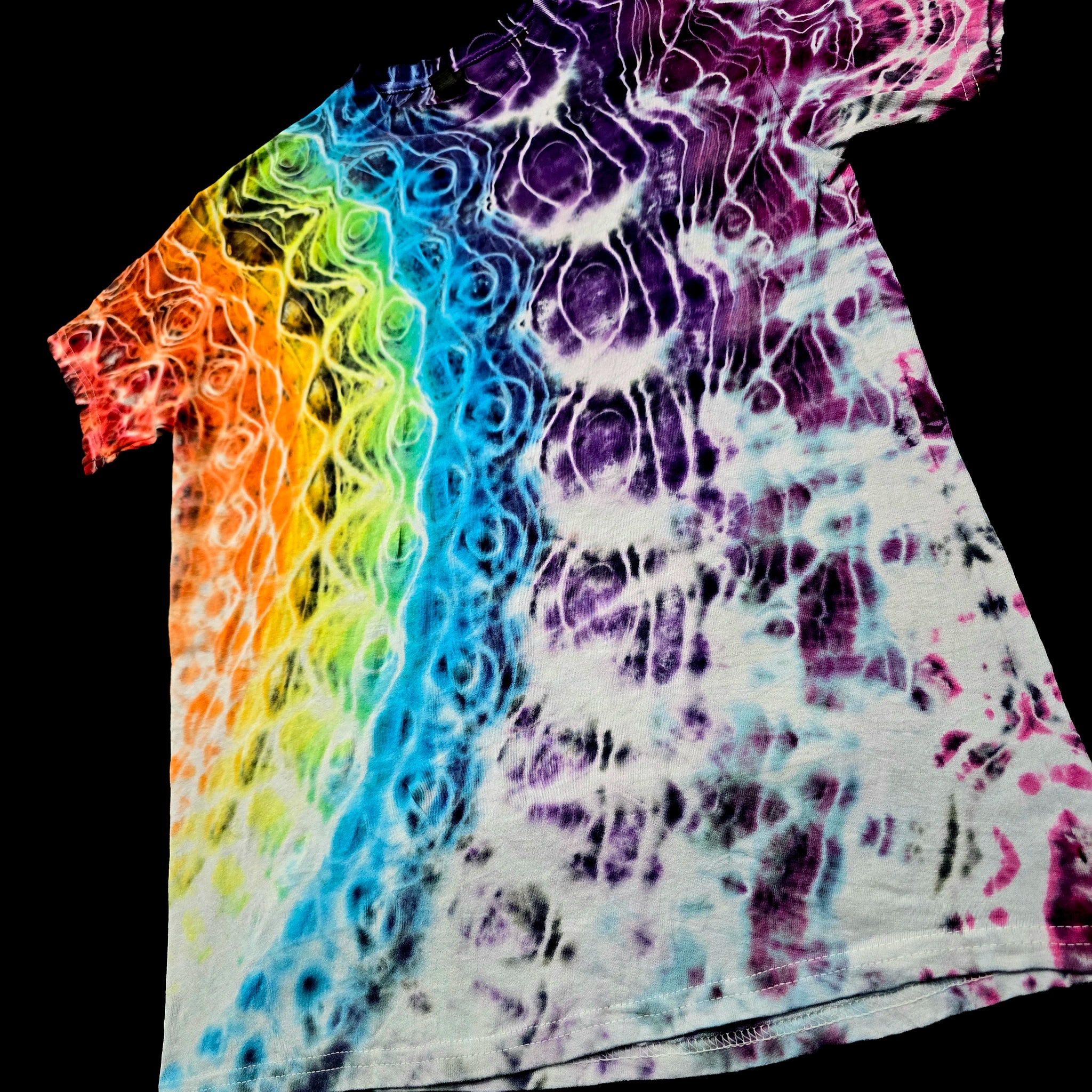 A short-sleeve tie-dye t-shirt featuring a vibrant rainbow gradient on the left side transitioning into purple, blue, and white marbled patterns on a black background.
