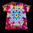 A short-sleeve crewneck tie-dye t-shirt featuring a vibrant, symmetrical kaleidoscopic mandala pattern in neon pink, yellow, blue, green, and white, displayed flat against a solid black background.
