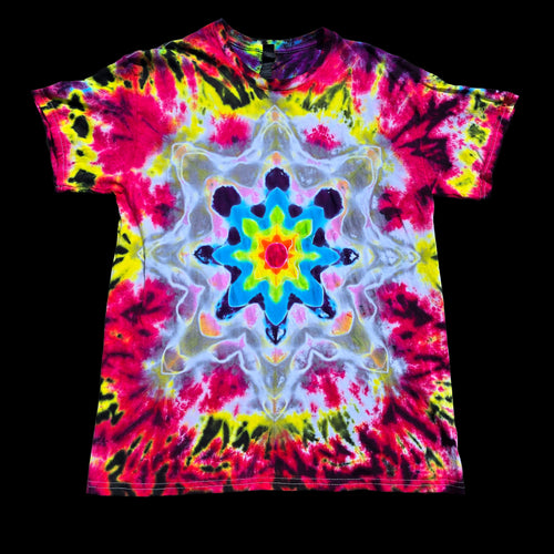 A short-sleeve crewneck tie-dye t-shirt featuring a vibrant, symmetrical kaleidoscopic mandala pattern in neon pink, yellow, blue, green, and white, displayed flat against a solid black background.