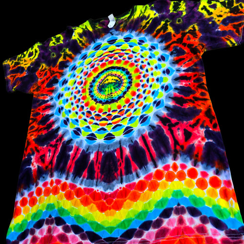 A short-sleeve tie-dye T-shirt laid flat against a black background, featuring a large psychedelic spiral mandala design in neon yellow, green, blue, red, orange, and purple with rainbow bands near the bottom.