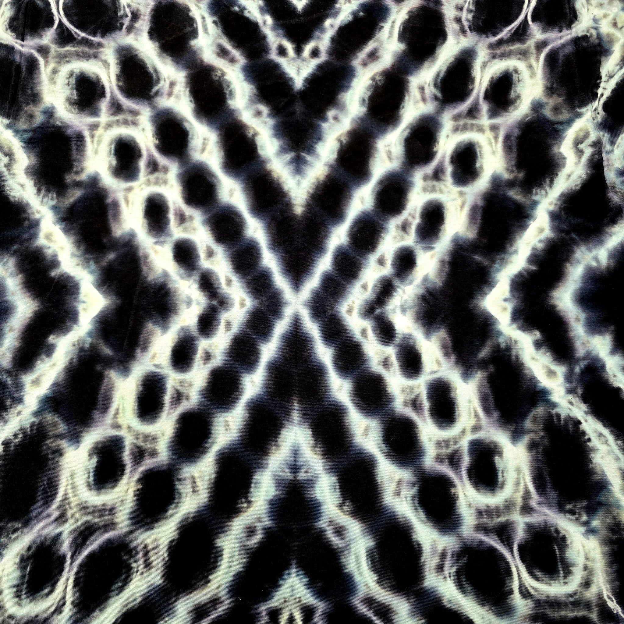 Abstract black and white tie-dye pattern with a symmetrical kaleidoscope design, featuring organic circular and oval shapes radiating from a central point.