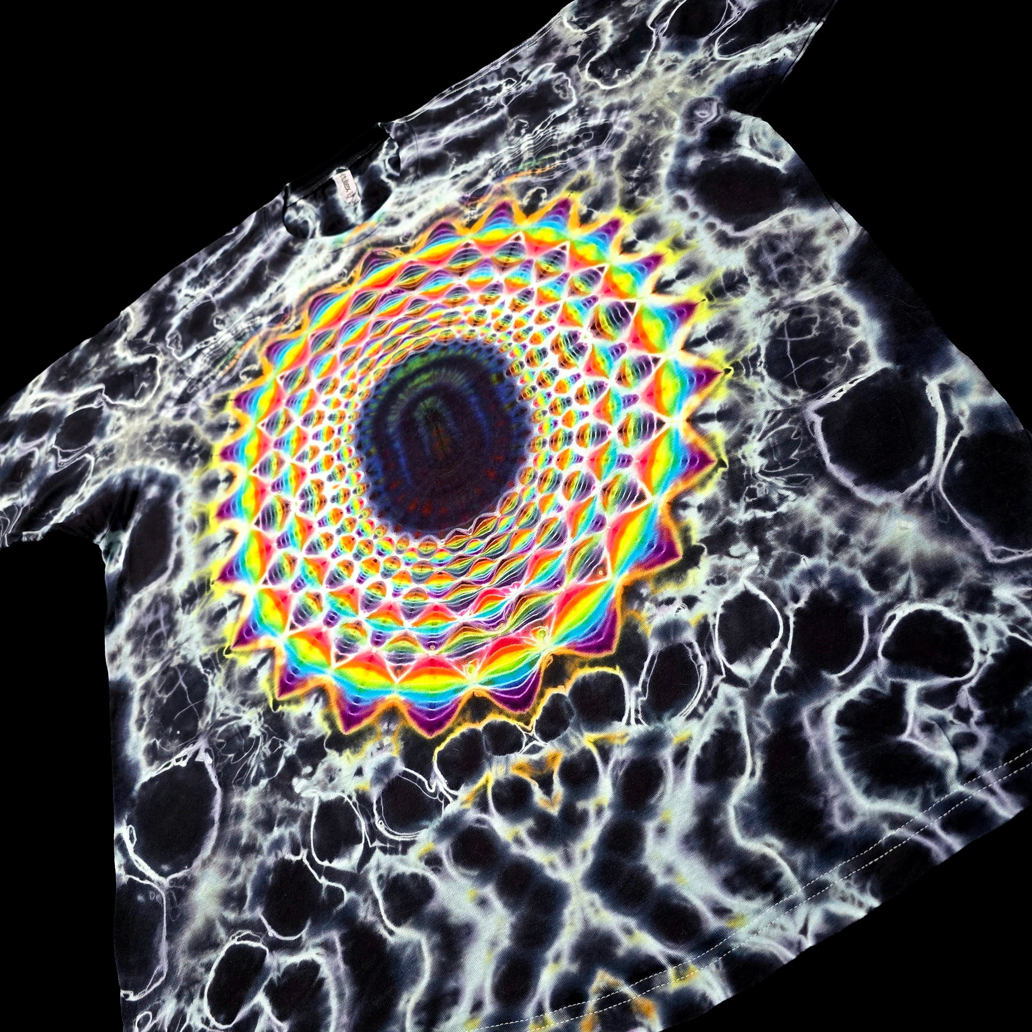 A black t-shirt featuring a highly detailed, colorful graphic print. The design displays a central kaleidoscopic mandala with rainbow-colored concentric rings and a dark blue center, surrounded by a white and black cellular or bone-like pattern.