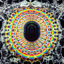 A highly symmetrical, psychedelic mandala pattern with concentric rings of rainbow colors including red, orange, yellow, green, blue, and purple on a black background with white web-like details.