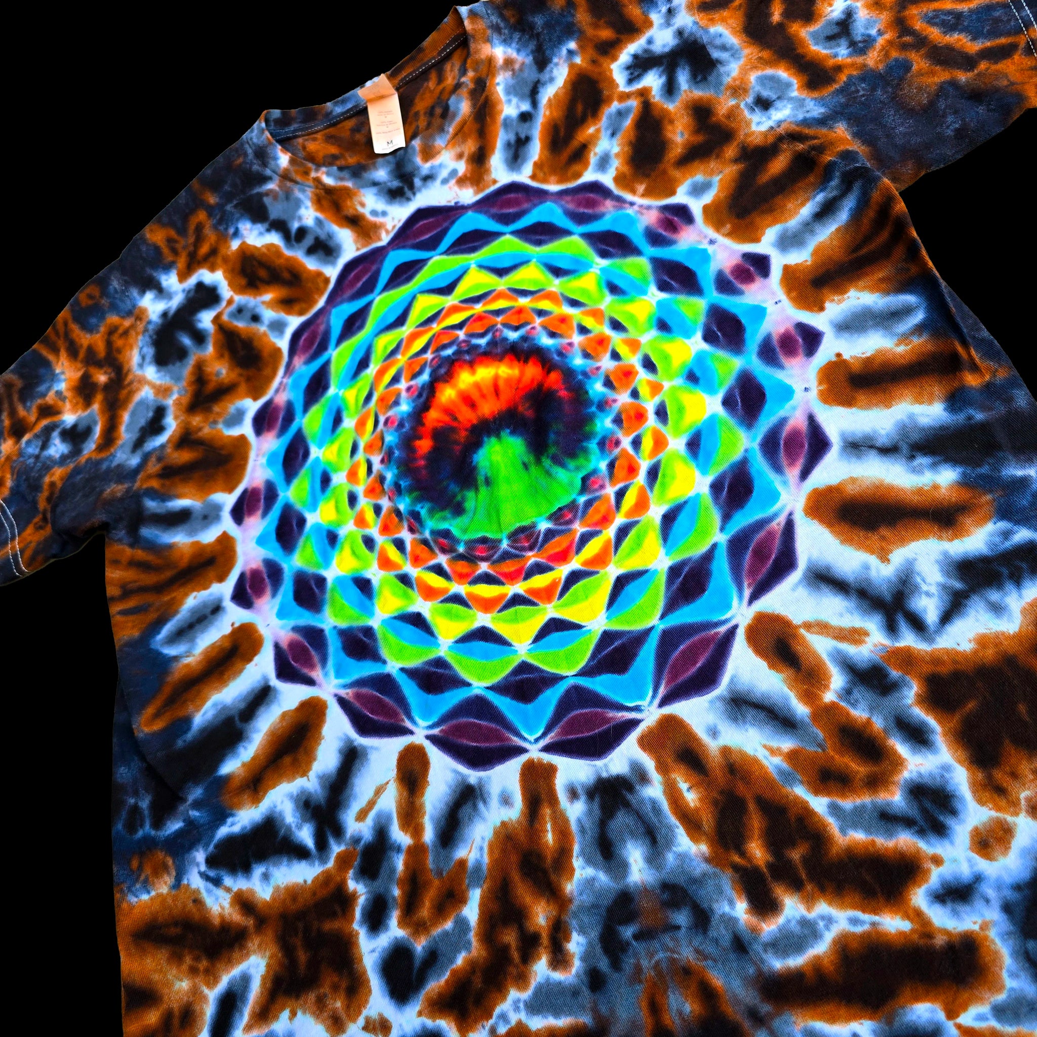 A short-sleeve tie-dye t-shirt featuring a vibrant, multicolored spiral mandala pattern in the center, surrounded by blue, brown, and orange tie-dye swirls.
