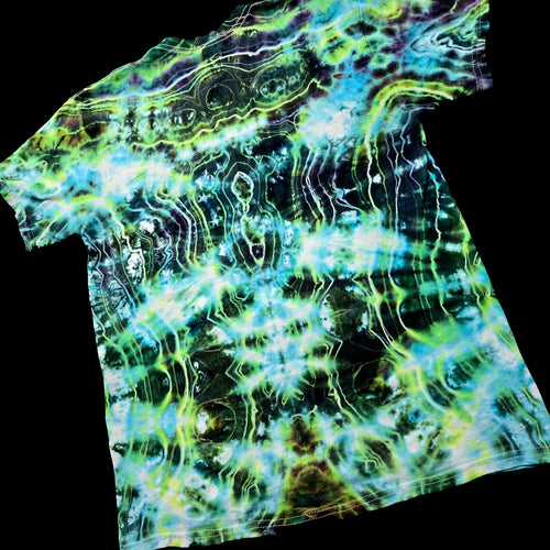 A short-sleeve crewneck t-shirt featuring a vibrant, psychedelic tie-dye pattern with swirling waves of neon green, cyan blue, lime yellow, and black, shown against a solid black background.