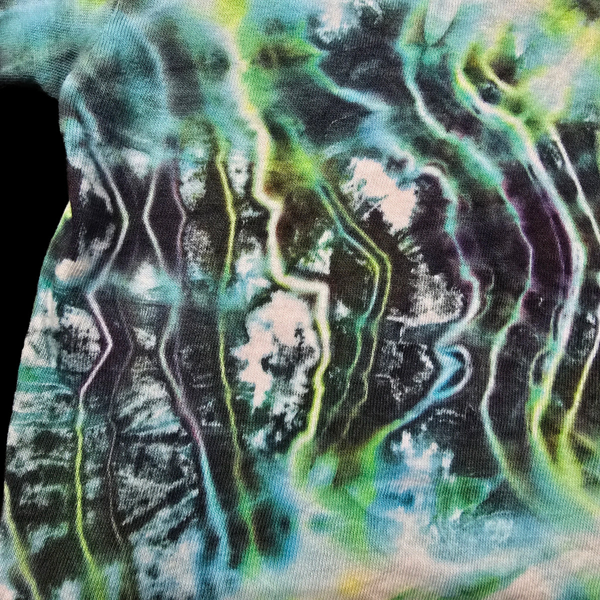 A close-up of a tie-dye fabric with a wavy, psychedelic pattern in shades of teal, green, black, purple, and white.