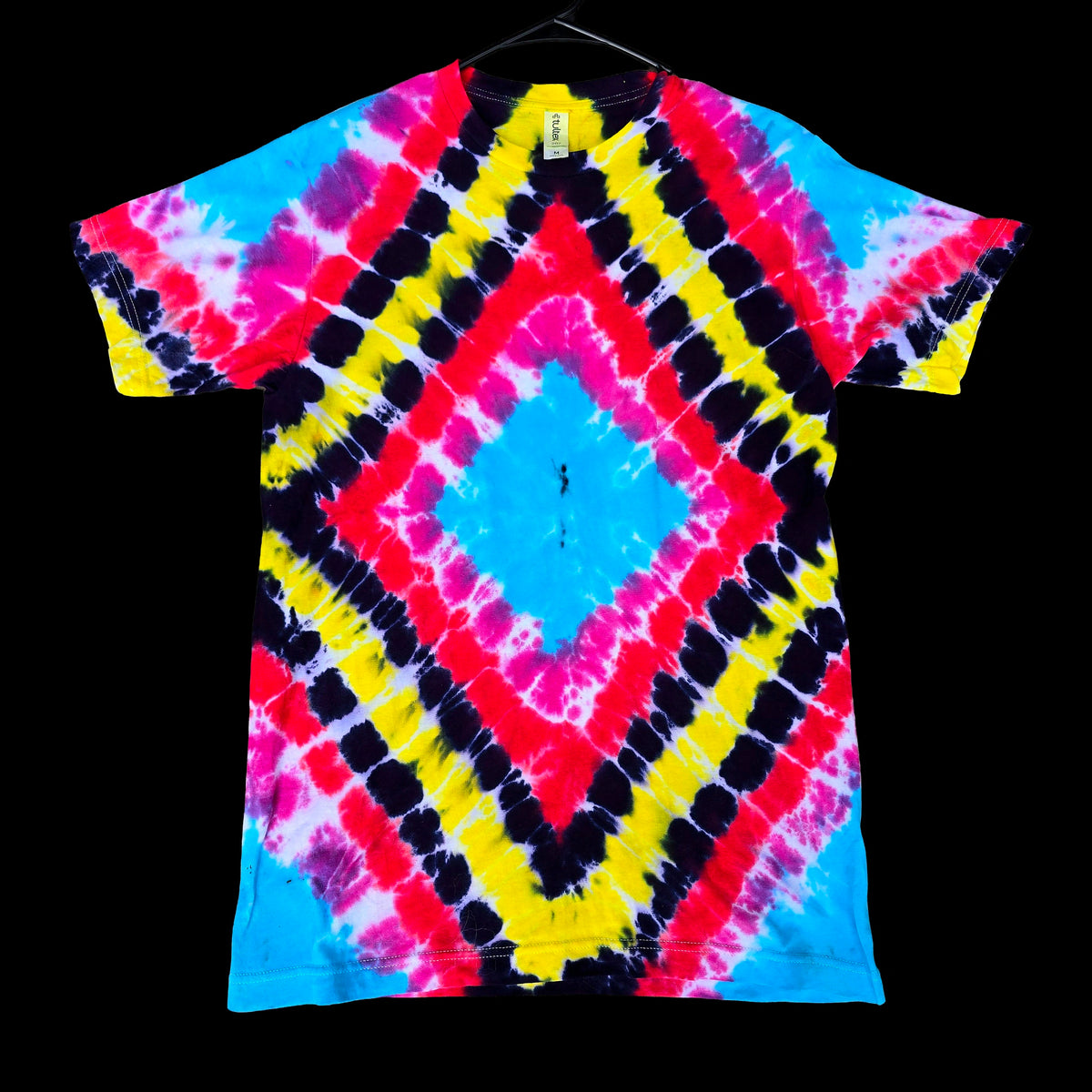 A short-sleeve tie-dye t-shirt featuring a bold geometric diamond pattern in neon pink, yellow, black, and blue, displayed flat against a solid black background.