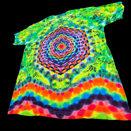 A short-sleeve tie-dye T-shirt laid flat on a solid black background, featuring a large multicolor mandala pattern in the center and rainbow stripes along the bottom hem.