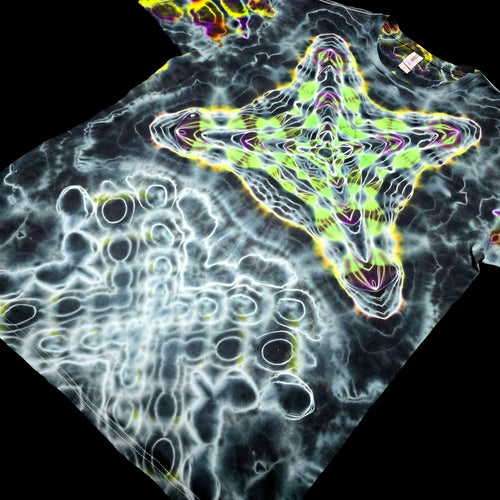 A black T-shirt laid flat on a black background, featuring a large neon green star-like graphic outlined in yellow and purple, with white bubble-like circular patterns across the rest of the shirt.