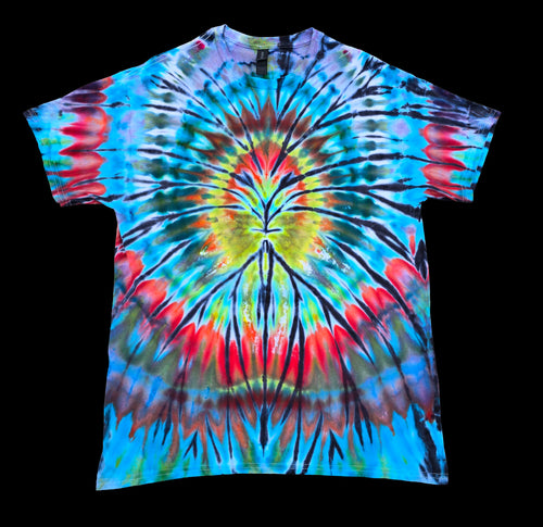 A short-sleeve tie-dye t-shirt with a vibrant spiral pattern in blue, red, yellow, green, and black, laid flat against a solid black background.