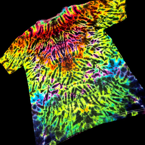 A short-sleeve tie-dye t-shirt with a vibrant spiral pattern of neon green, yellow, orange, pink, purple, and blue, displayed against a solid black background.