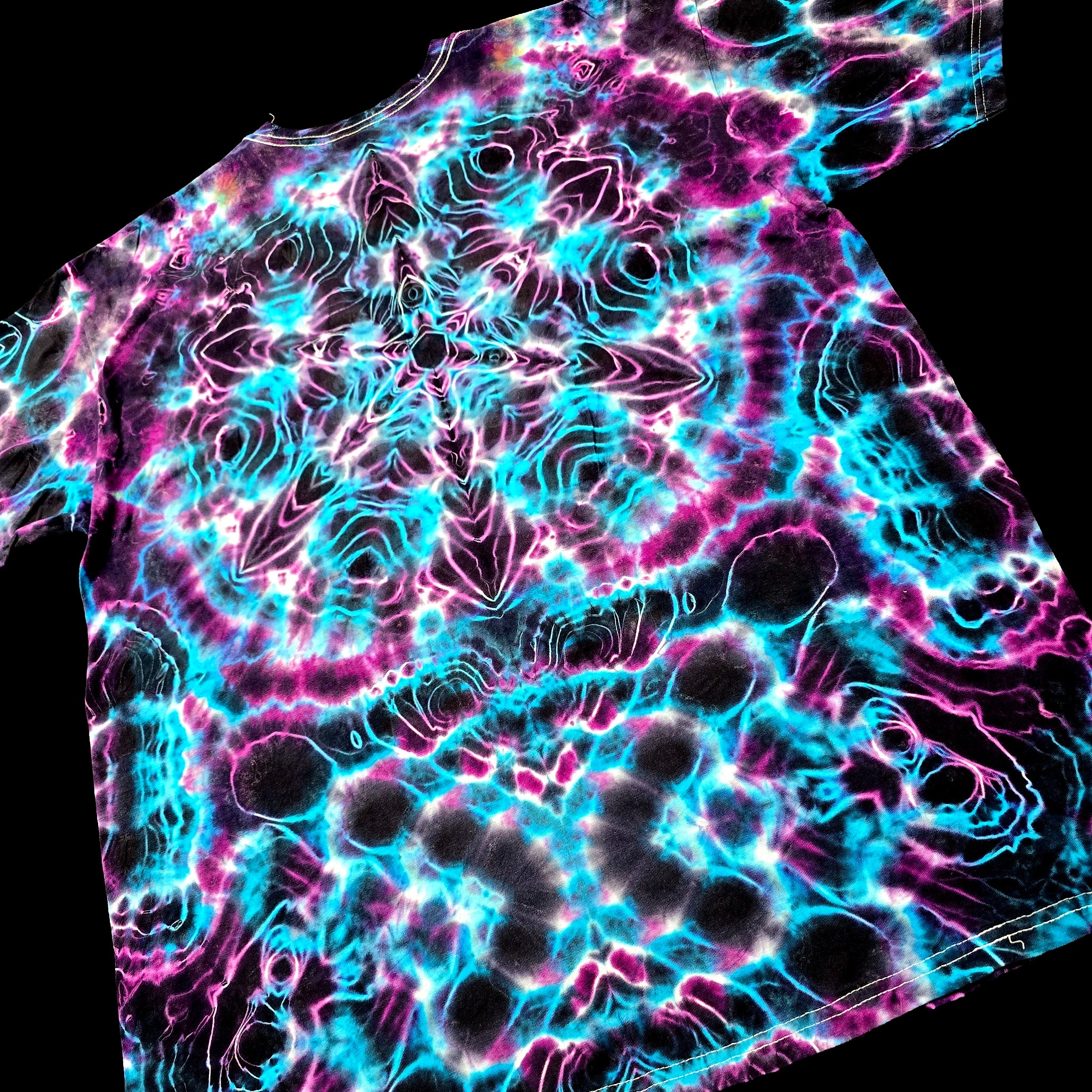 A short-sleeve t-shirt featuring a vibrant, psychedelic tie-dye pattern with swirling neon cyan, magenta, and black, shown against a solid black background.