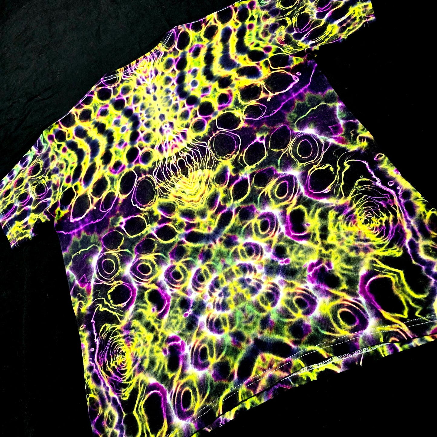 Neon patterned fabric with purple and yellow colors on a black background