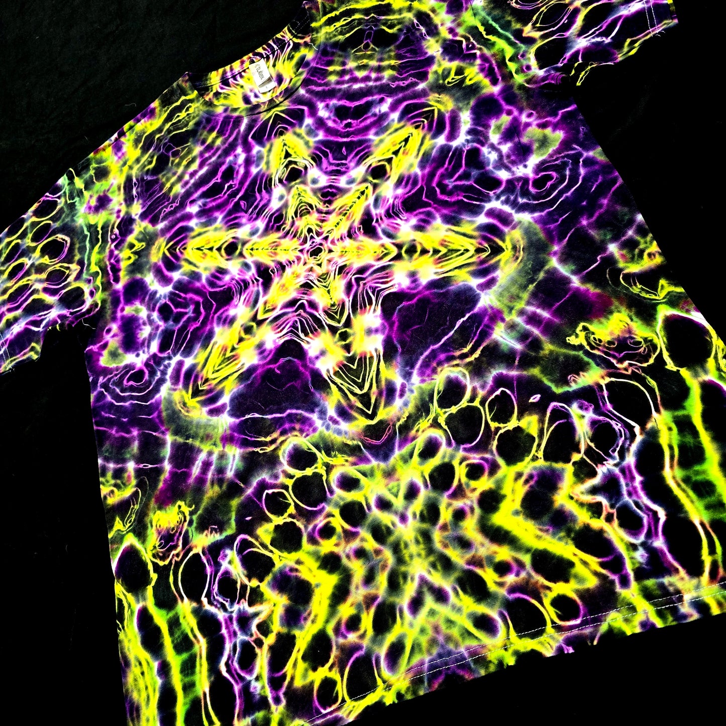 Tie-dye shirt with vibrant purple and yellow patterns on a black background