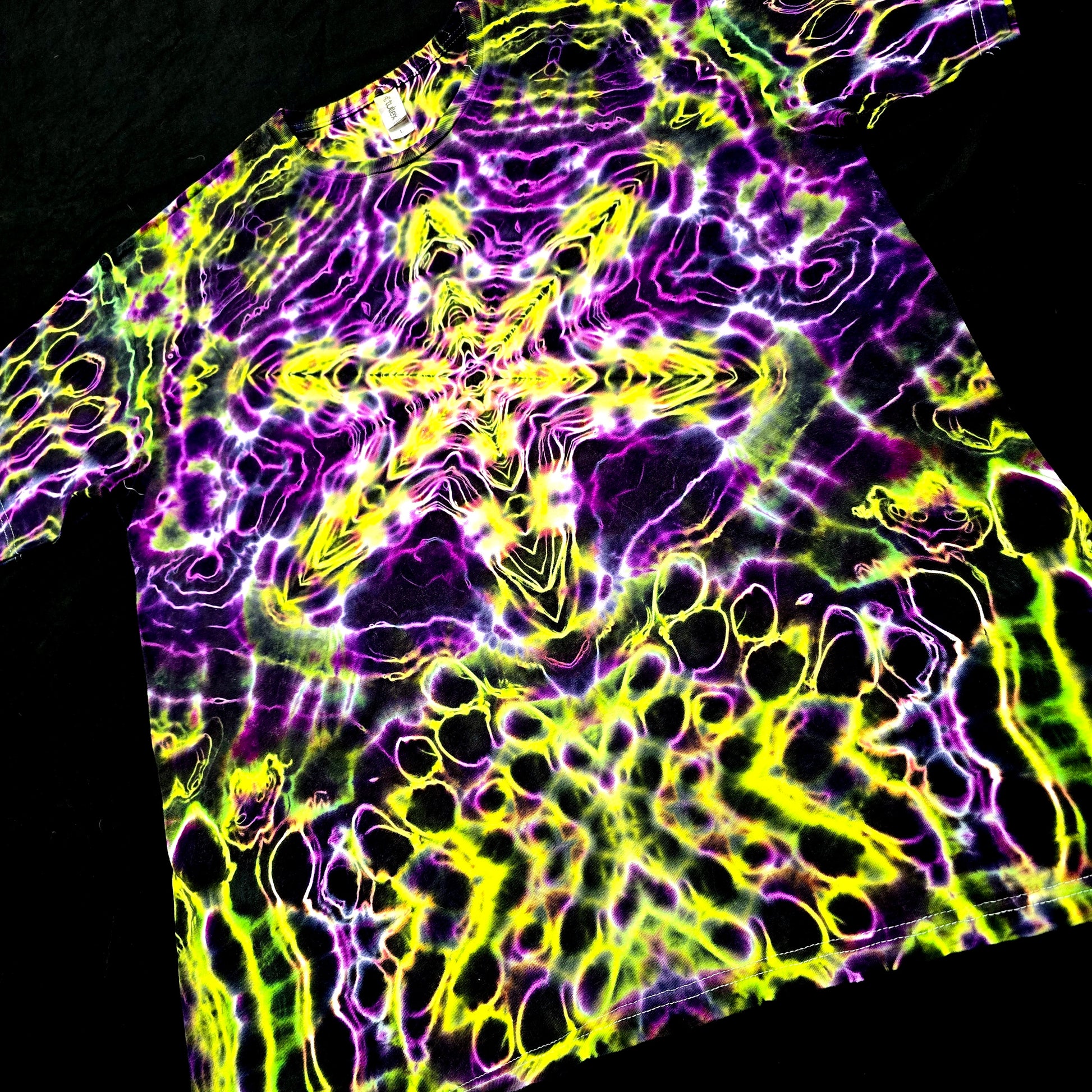 Tie-dye shirt with vibrant purple and yellow patterns on a black background