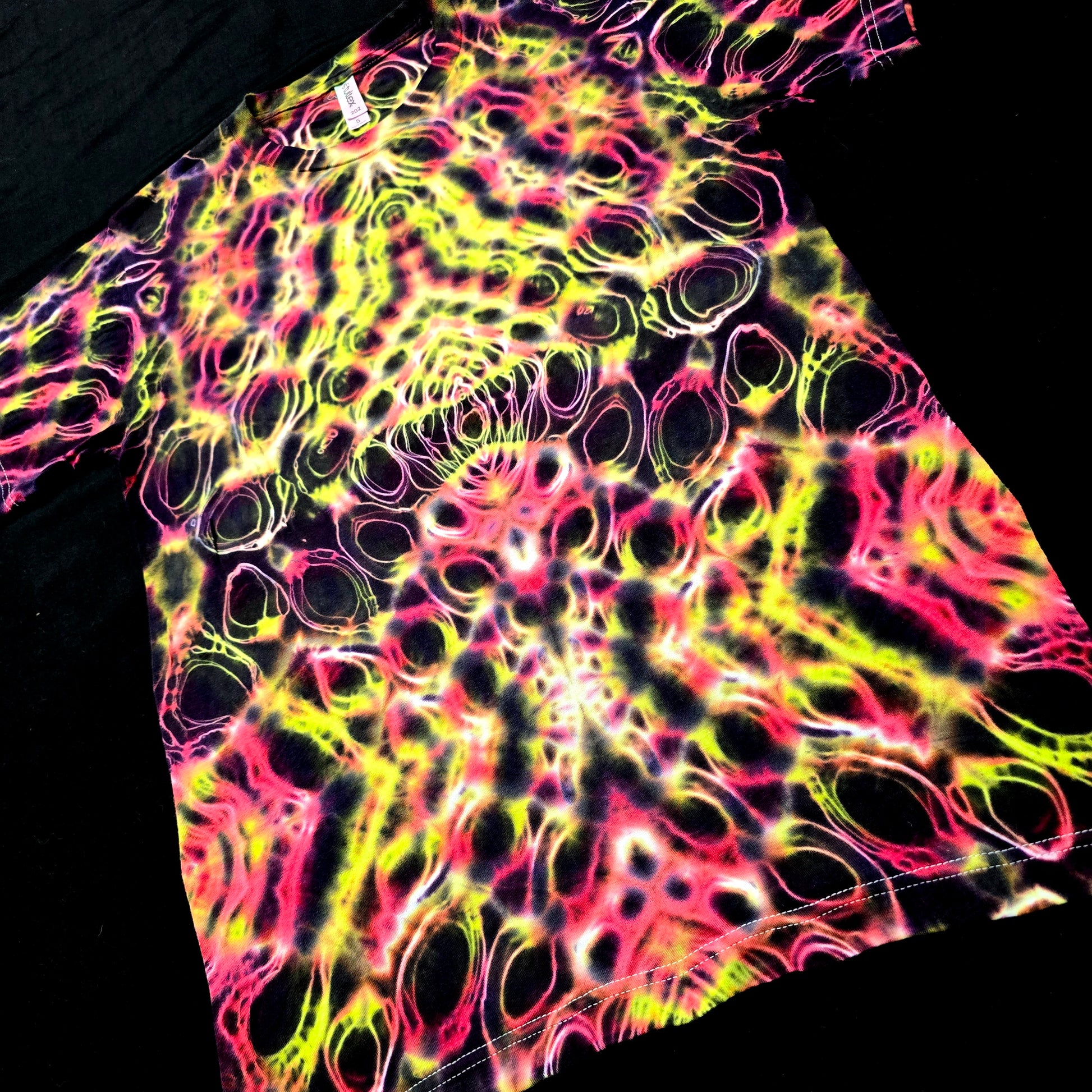 Close-up of mirrored psychedelic tie-dye pattern with neon pink and electric yellow details