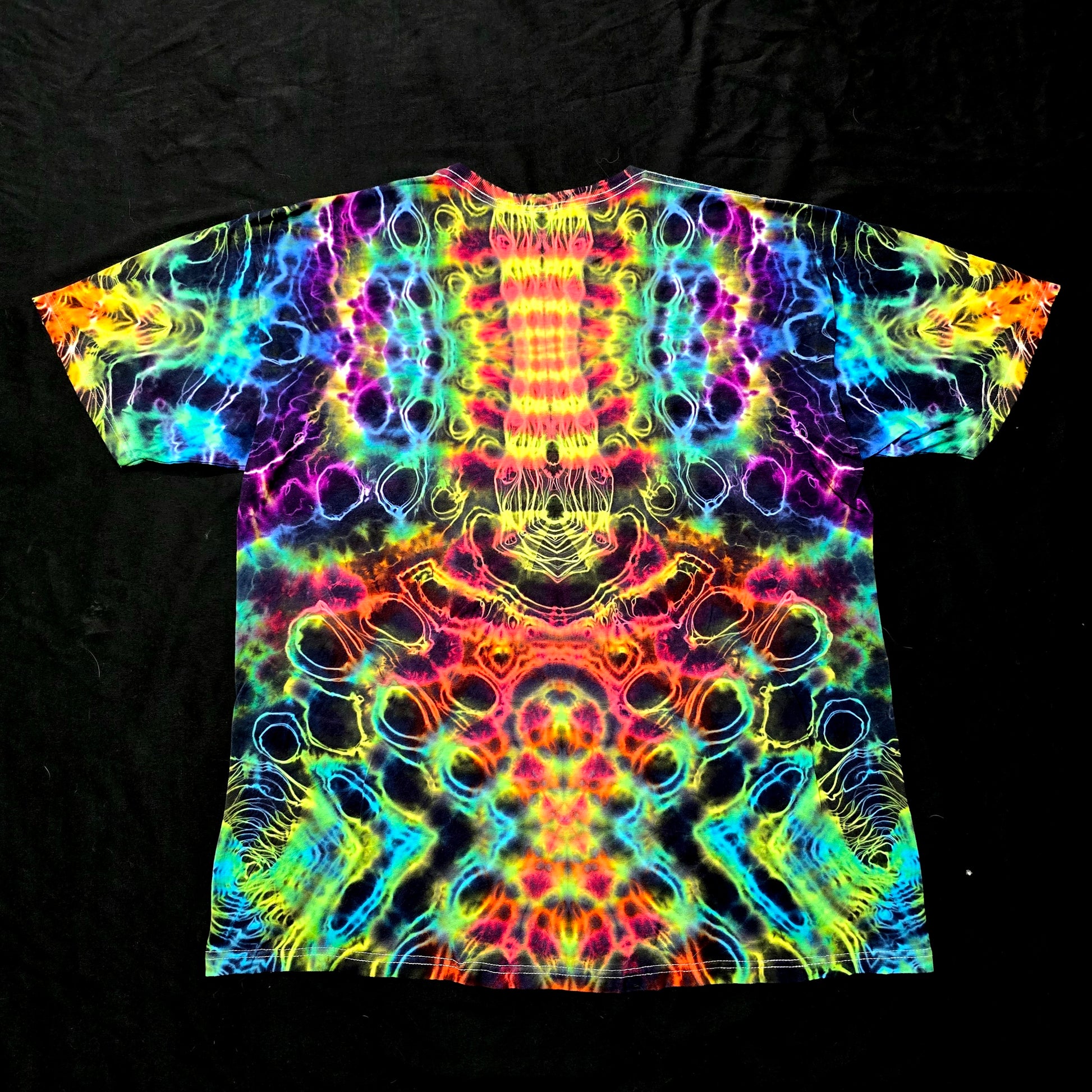 Back view of Prism Core tie-dye shirt showing symmetrical hyper fractal and hyper spine design in neon rainbow tones

