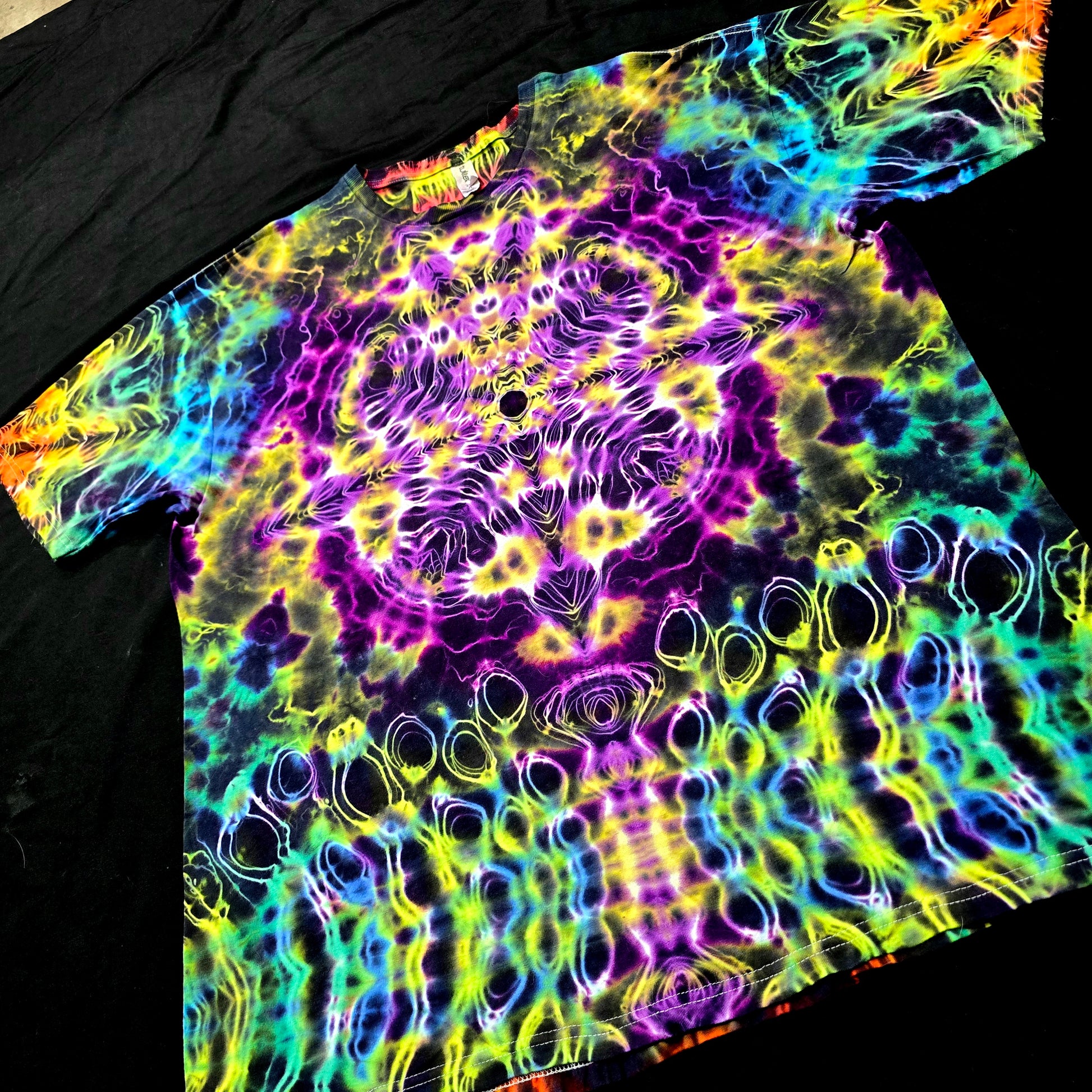 Angled front view highlighting the hyper fractal star symmetry and vibrant color transitions of the Prism Core tie-dye tee

