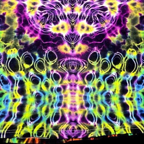 A close-up of a tie-dye fabric with a highly symmetrical, kaleidoscopic pattern in neon purple, yellow, green, blue, and black.