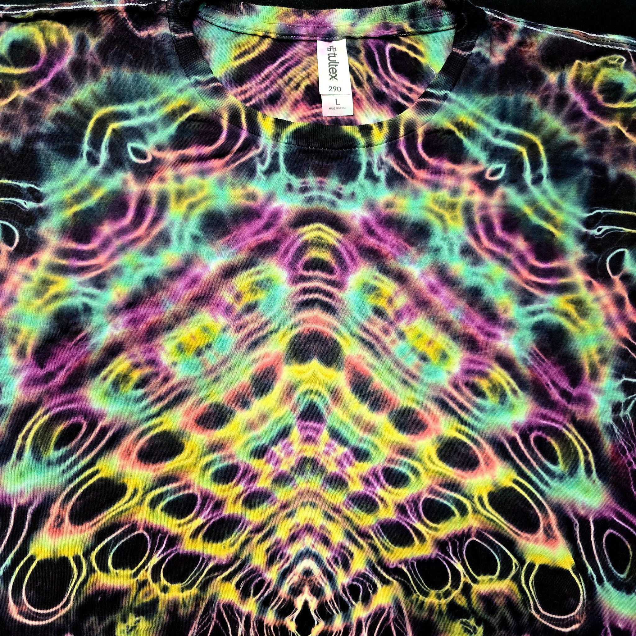Tie-dye patterned shirt with a visible brand tag on a black background