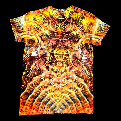 A short-sleeve crewneck t-shirt featuring a vibrant, symmetrical psychedelic flame-like pattern in yellow, orange, red, and black, displayed flat against a solid black background.