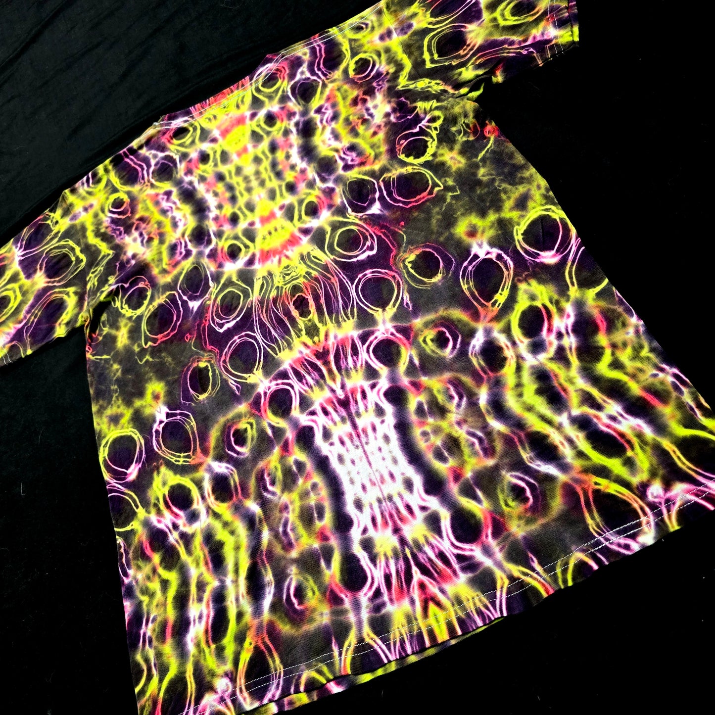 Angled back view emphasizing continuous symmetry and electric dye flow across shoulders and spine
