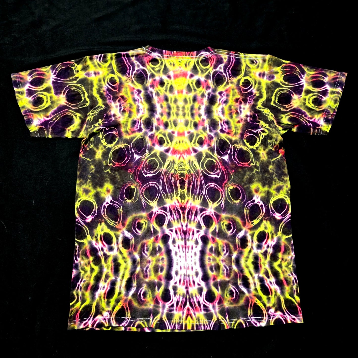 Back view of Solar Pulse Veil tie-dye shirt showing mirrored Hyper Spine symmetry with glowing neon dye lines

