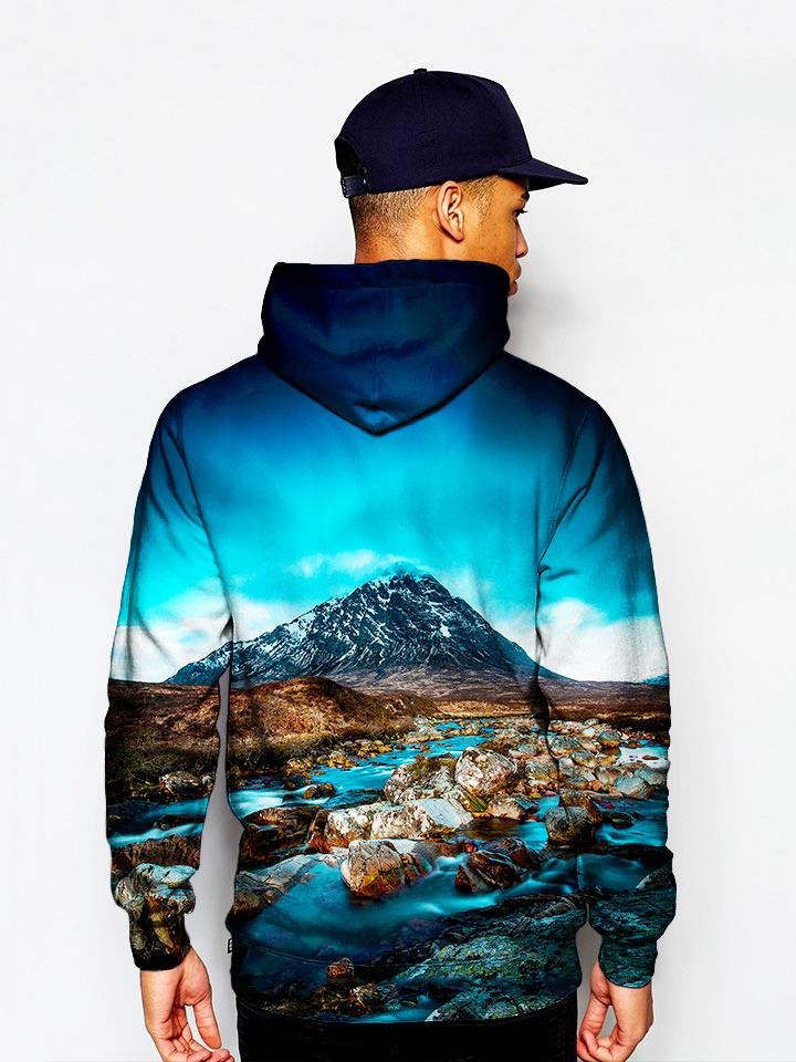 Model in pullover hoodie with blue sky, mountain and flowing river all over print